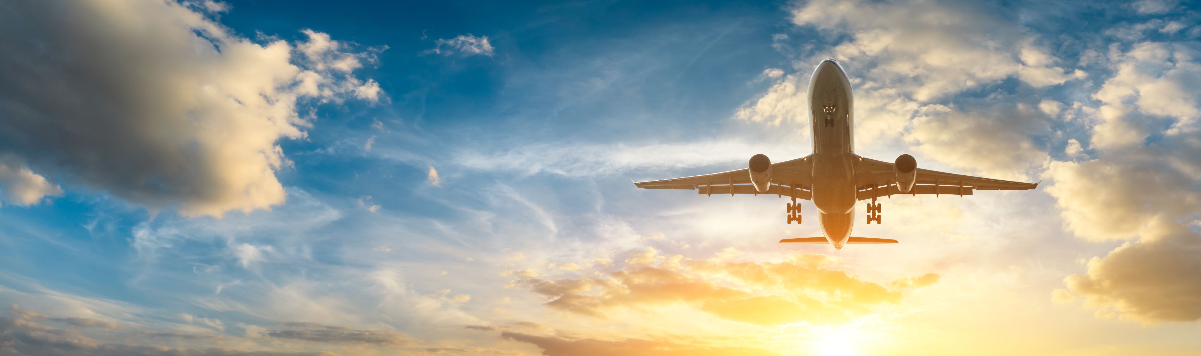 airline flying through clouds at sunrise